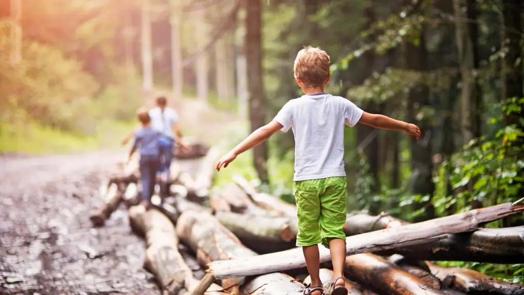niño caminando por tronco con amigos