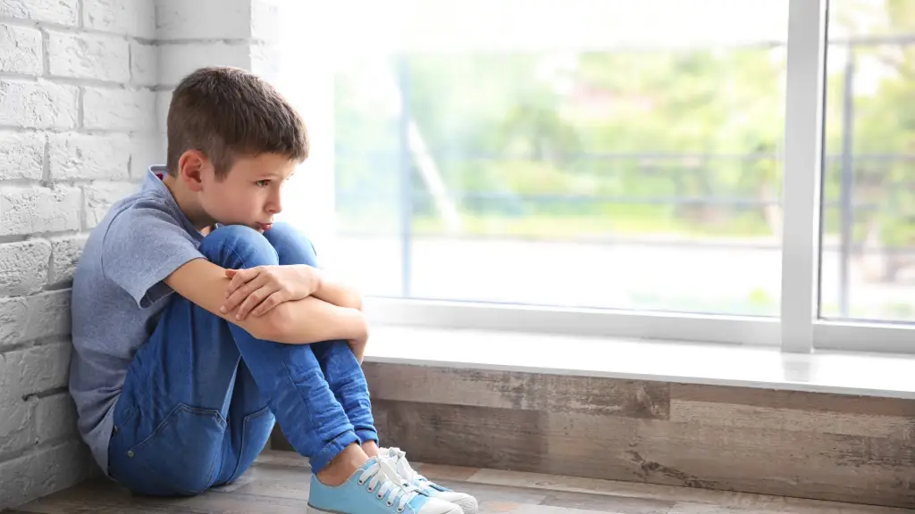 niño triste sentado cerca de una ventana